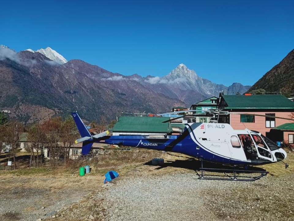 A helicopter on the helipad of a mountain lodge